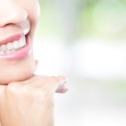 Beautiful young woman teeth close up with copy space on the right side. Isolated over green background, asian beauty model